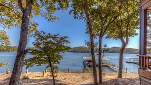Un chalet au bord du lac, doté d’un quai, entouré d’arbres et offrant une vue dégagée sur le lac.