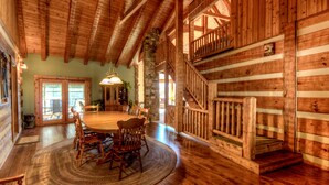 Un intérieur spacieux en bois, avec une grande table à manger, un escalier en bois et un pilier en pierre.