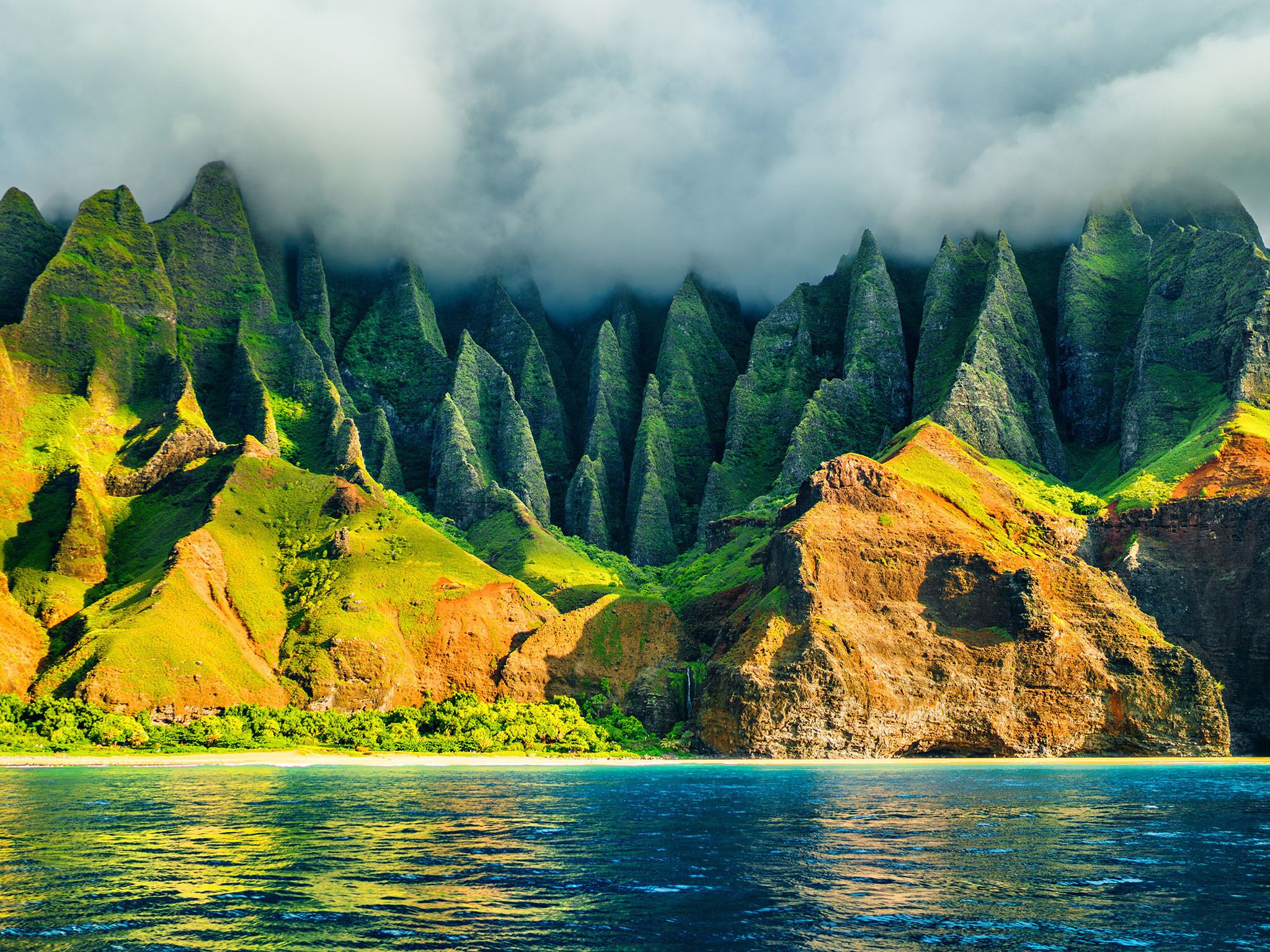A coastal landscape with green hills and a clear blue sea.