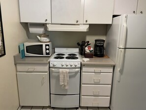 A compact kitchen with a stove, microwave, and refrigerator.