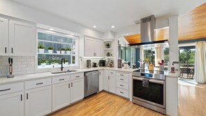 A modern kitchen with white cabinetry, a stainless steel oven, and a dishwasher. - Spacious 4BD Beach House - Pet-Friendly - Hot Tub! (Manzanita)