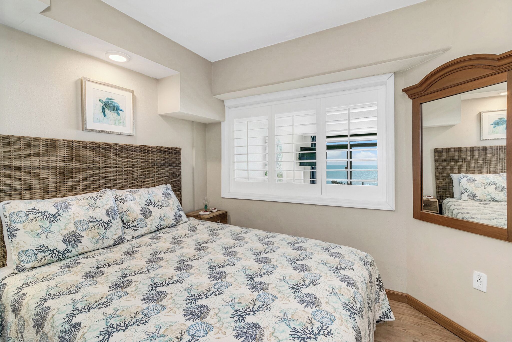 Un dormitorio con una cama grande, una ventana con persianas, un cabecero de mimbre y un cuadro enmarcado en la pared.