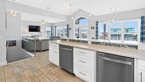 Una cocina moderna con muebles blancos, lavavajillas y un amplio ventanal con vistas al exterior.