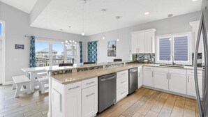 Una cocina moderna con armarios blancos, una isla central y un ventanal grande.