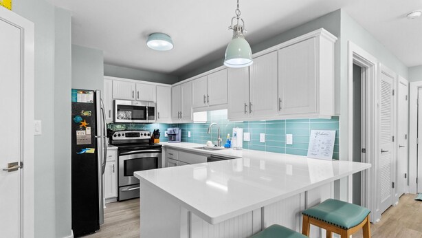 Une cuisine moderne avec des meubles blancs, un îlot central et un luminaire suspendu.