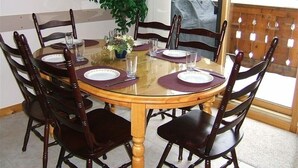 Een eethoek met een ronde tafel, zes stoelen en een potplant.