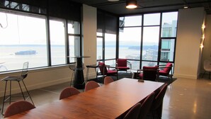 A conference room with a large wooden table, red chairs, and a view of the water through large windows. - Harbor Steps - 1 Blk to Pike Place Market, Waterfront - City Views! (Seattle)