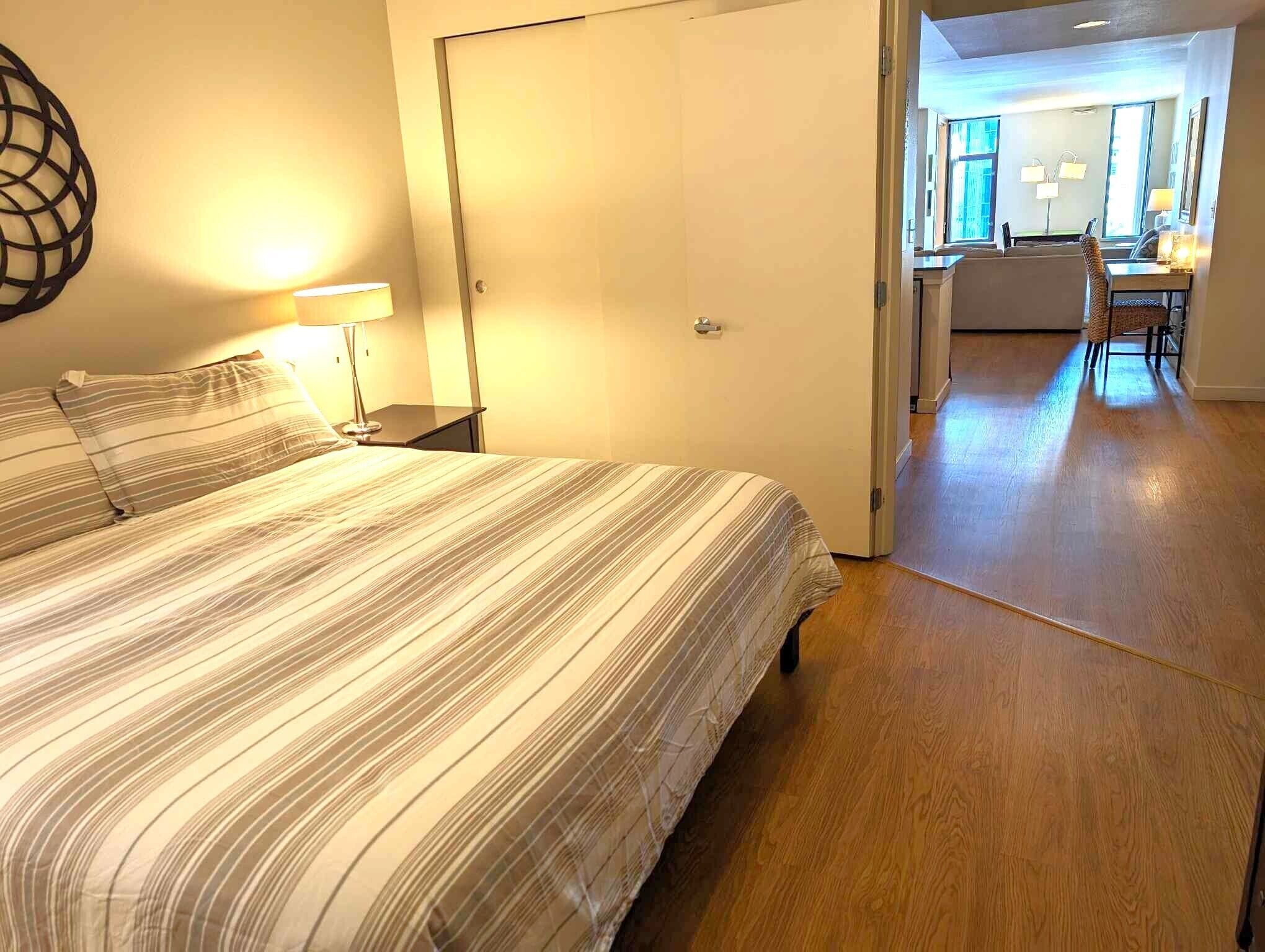 Een hotelkamer met een bed, een bedlampje en uitzicht op de eetruimte.