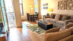 A living room with a sofa, ottoman, and a dining area with chairs and a table. - Harbor Steps - 1 Blk to Pike Place Market, Waterfront - City Views! (Seattle)