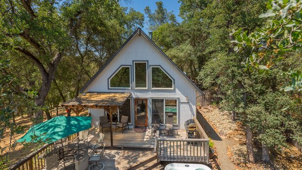 A house with a large deck, outdoor seating, and a hot tub. - Cozy Cottage Retreat,  Close to Yosemite, Beautiful Views, Hot Tub & More! (Mariposa)