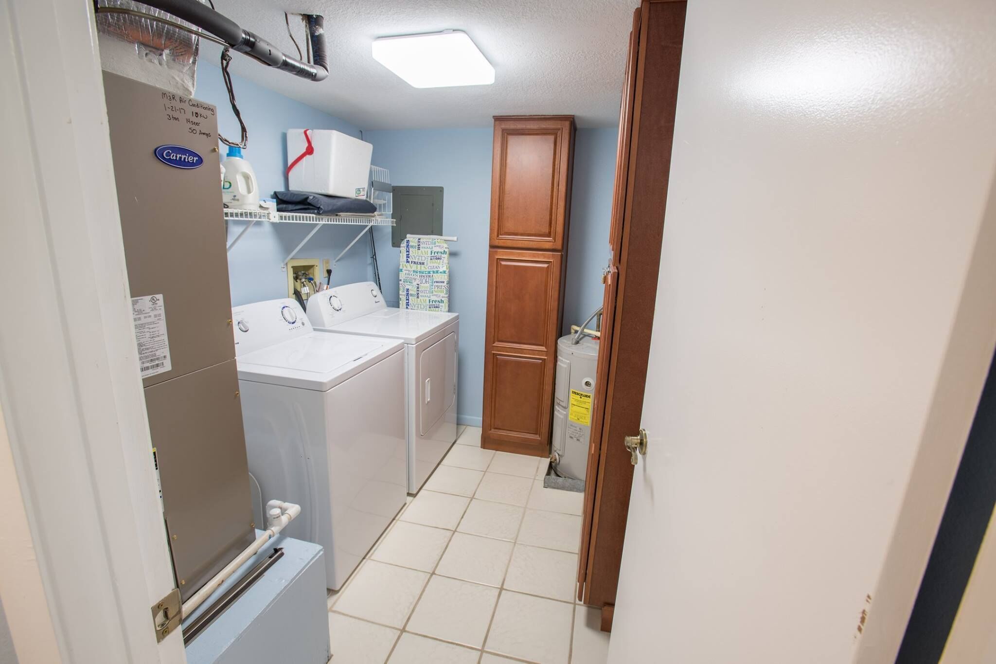 A laundry room with a washer and dryer, a cabinet, and a utility area with a water heater.