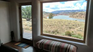 A room with a large window overlooking a lake and hills. - Stellar, Southwest, Luxury home.  Extraordinary location on Abiquiu Lake (Gallina)