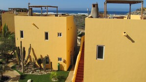 A yellow building with multiple windows and a view of the ocean. - Puesta Del Sol Top Unit 2BR Condo Private Rooftop+ Steps to Cerritos Surf Beach (Cerritos Beach)