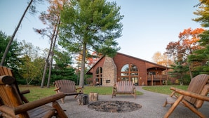 Eine Lodge mit Steinaußenwand, Holzbalkon und Adirondack-Stühlen.