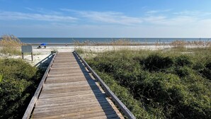 A wooden boardwalk leading to a beach with sand and sparse vegetation. - Peek of Blue – 2nd Row Sea Pines Home, Pool & Spa, Sleeps 17, 800 Ft to Beach (Hilton Head Island)