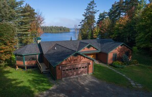 Una baita con garage, un portico coperto e vista su un lago.
