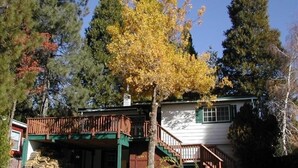 Une maison à deux étages avec une terrasse en bois et un porche couvert.