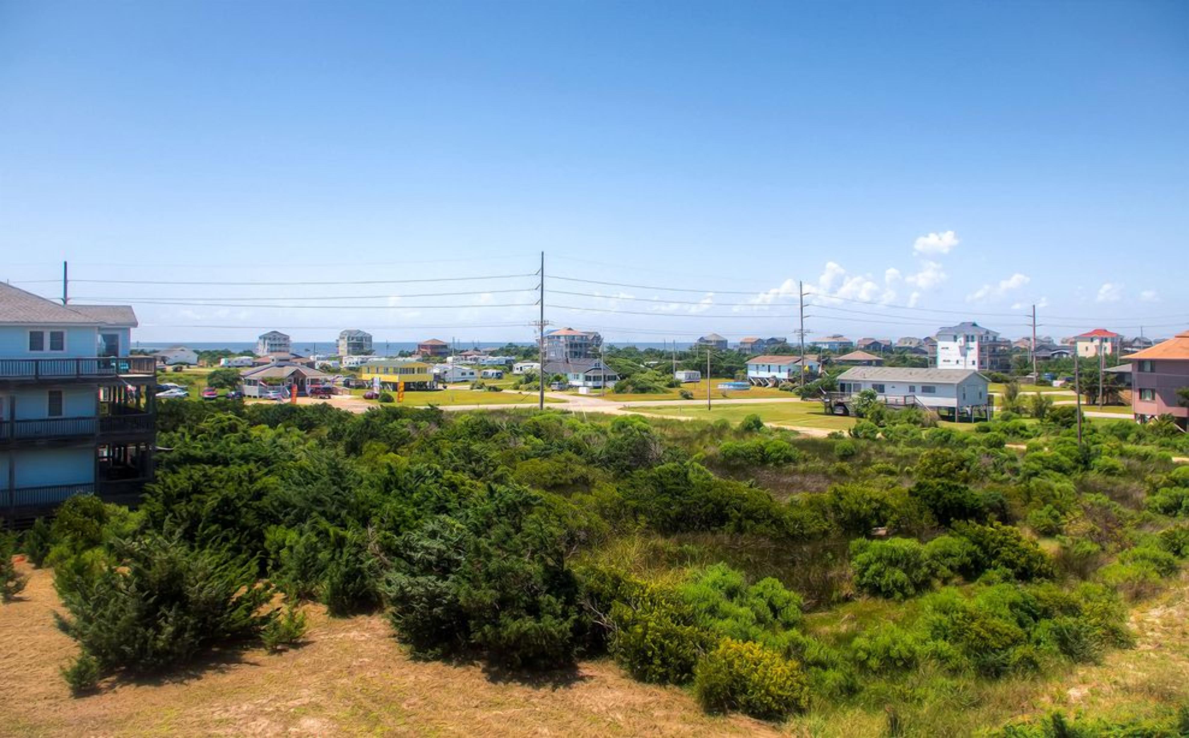 A residential area with houses, a clear sky, and a view of the ocean.