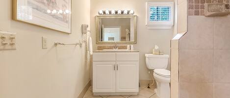 A bathroom with a vanity, a mirror, a toilet, and a shower area.