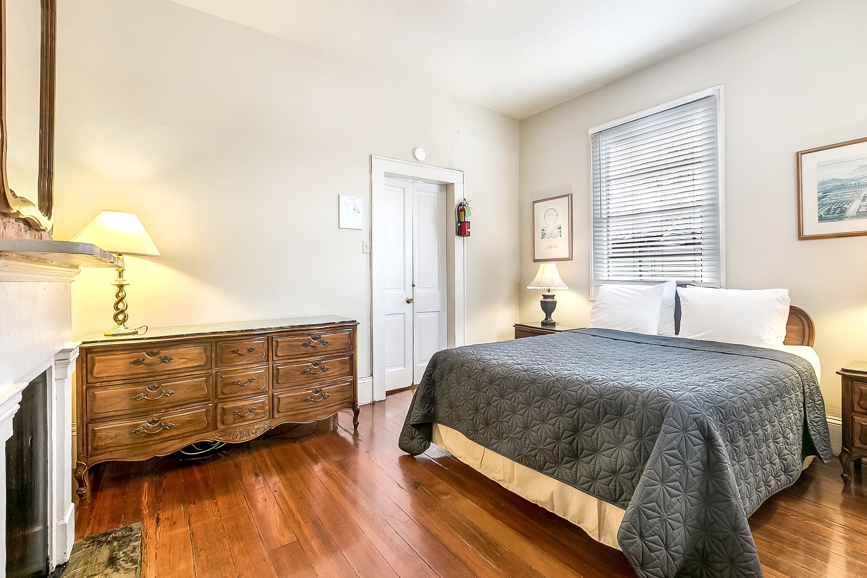 A bedroom with a large bed, wooden dresser, and two bedside tables.