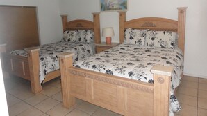 Een slaapkamer met twee houten bedden, een plafondventilator, een schilderij en een bedlampje.