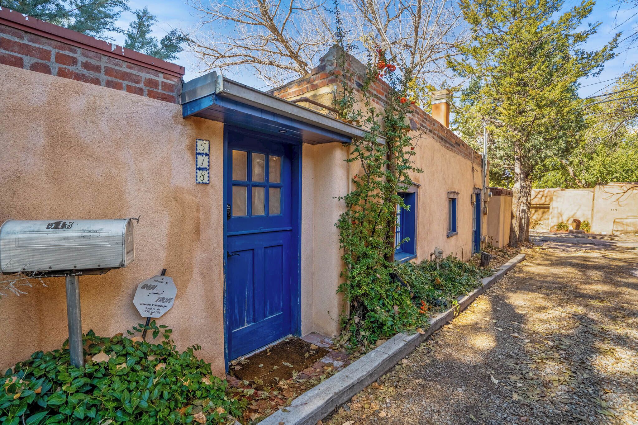 Una casa tradicional con una puerta azul, un buzón y un pequeño jardín.