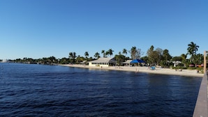 Una playa con un edificio de fachada blanca y techo azul.