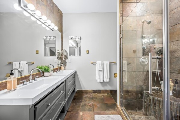 Un baño moderno con tocador, espejos y cabina de ducha acristalada.