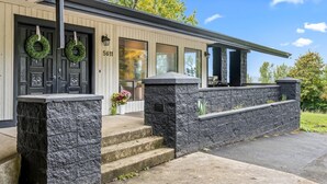 A modern building with a stone facade, a black door with a green wreath, and a number '5611' above the door.