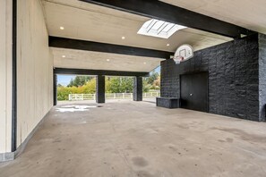 Een overdekte binnentuin met een basketbalring, een dakvenster en een stenen muur.