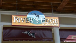 Letrero de 'River's Edge' con un logo de ave y 'Apalachicola' escrito debajo.