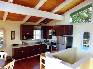 A modern kitchen with dark wooden cabinets, stainless steel appliances, and a large island. - Hip, Secluded 2BR/2BA Cabin Unmatched Panoramic Views and Charm Among the Pines (Idyllwild-Pine Cove)
