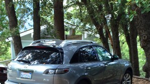 Un VUS argenté était garé sur un chemin de gravier, entouré d’arbres.