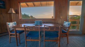 Un tavolo da pranzo in legno con sedie imbottite blu, una finestra vista alberi e una porta con pannello in vetro.