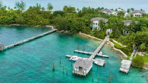 An aerial view of a coastal property with a dock, clear turquoise waters, and lush greenery. - On Beach Time |Lux Villa|Oceanfront|Heated Pool (Nassau)
