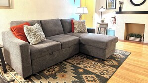 A living room with a grey sectional sofa, patterned rug, and a fireplace. - Perfect family friendly home in Nob Hill (Albuquerque)