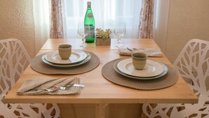 A dining table set with plates, bowls, and a bottle of Pellegrino water, surrounded by white chairs. - Perfect family friendly home in Nob Hill (Albuquerque)