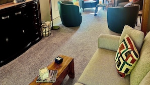 Een woonkamer met een bank, fauteuils, een salontafel, een televisie en een houten kast.
