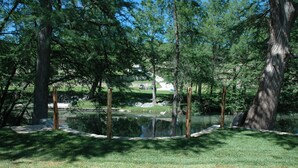 Un parc tranquil amb un estany, envoltat d'alzines altes i una zona verda.