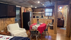 Habitació acollidora amb un llit, televisió, taula de menjador amb cadires i zona de cuina amb nevera, microones i rentamics.