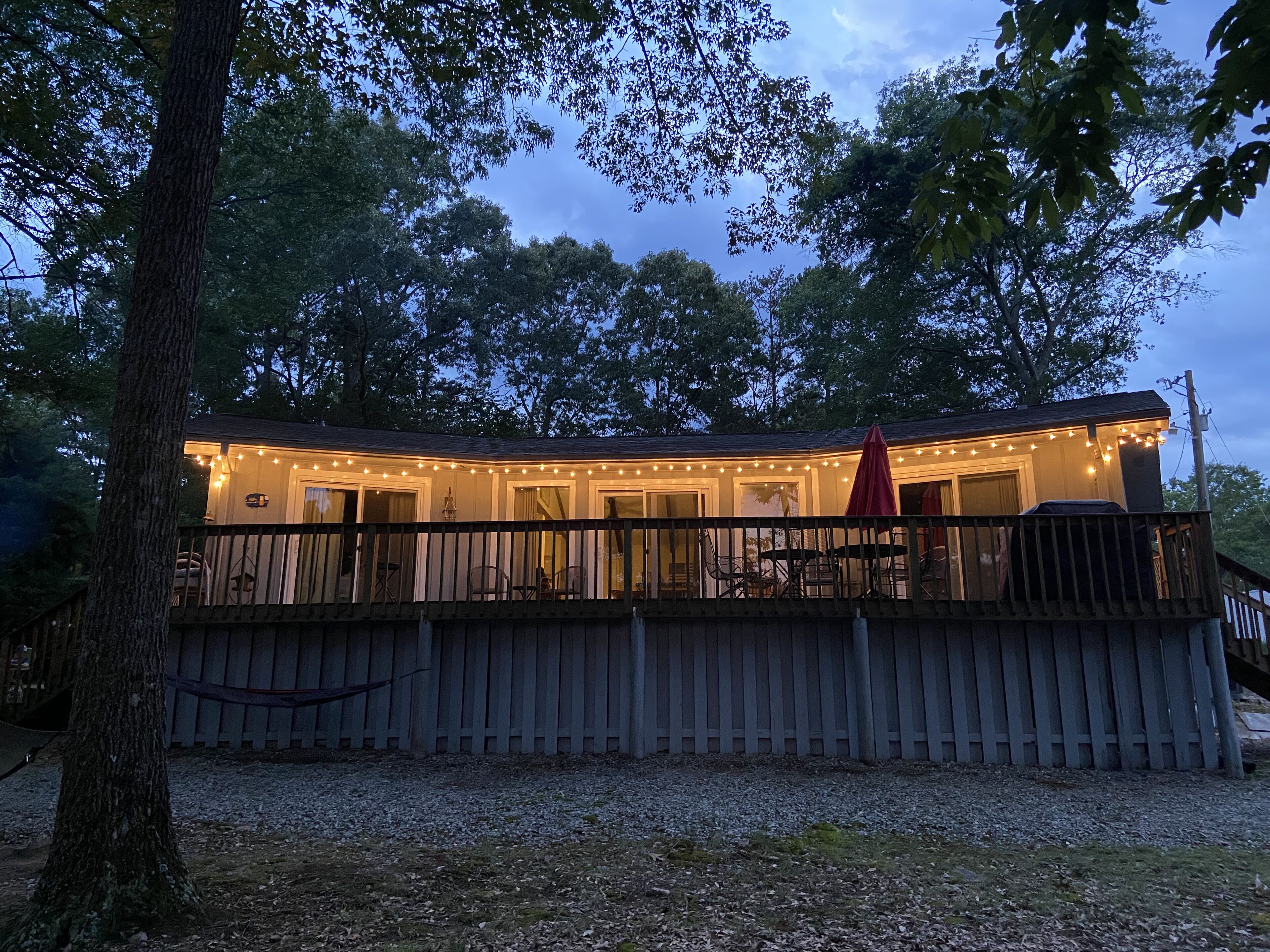 A wooden deck with a covered seating area, surrounded by trees.