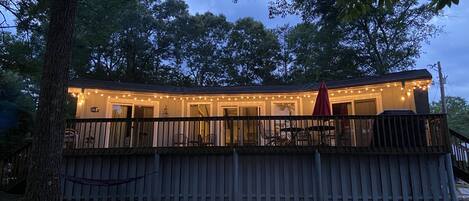 A wooden deck with a covered seating area, surrounded by trees.