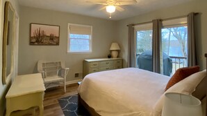 A bedroom with a bed, a chair, a desk, a lamp, a ceiling fan, a window, and a view of the outdoors.