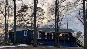 A two-story house with a deck, surrounded by trees.