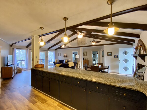A spacious kitchen with dark cabinetry, a granite countertop, and pendant lighting.