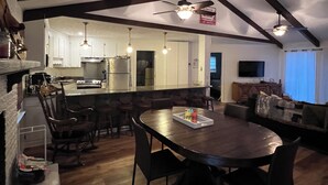 A spacious kitchen with a central island, wooden dining table, and bar stools.