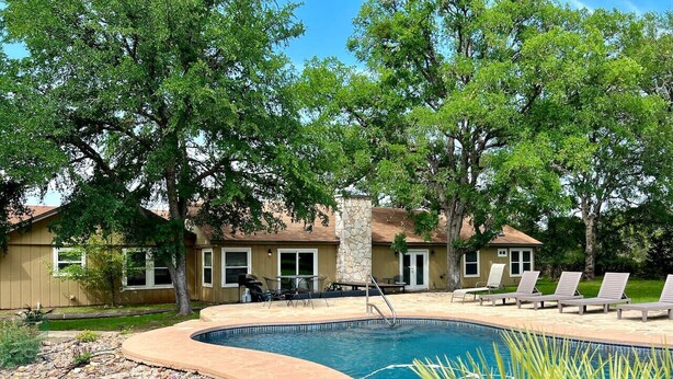 A swimming pool with a curved edge, surrounded by a patio area with lounge chairs. - 7-Acre Hill Country Haven w/ POOL-Guadalupe River (Bergheim)