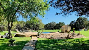 A stone pathway leading to a pool area with a small house in the background. - 7-Acre Hill Country Haven w/ POOL-Guadalupe River (Bergheim)