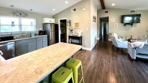 A spacious kitchen with a large island, green bar stools, and a ceiling fan. - 7-Acre Hill Country Haven w/ POOL-Guadalupe River (Bergheim)