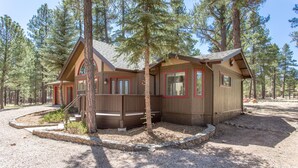 A cabin with a deck, surrounded by trees.